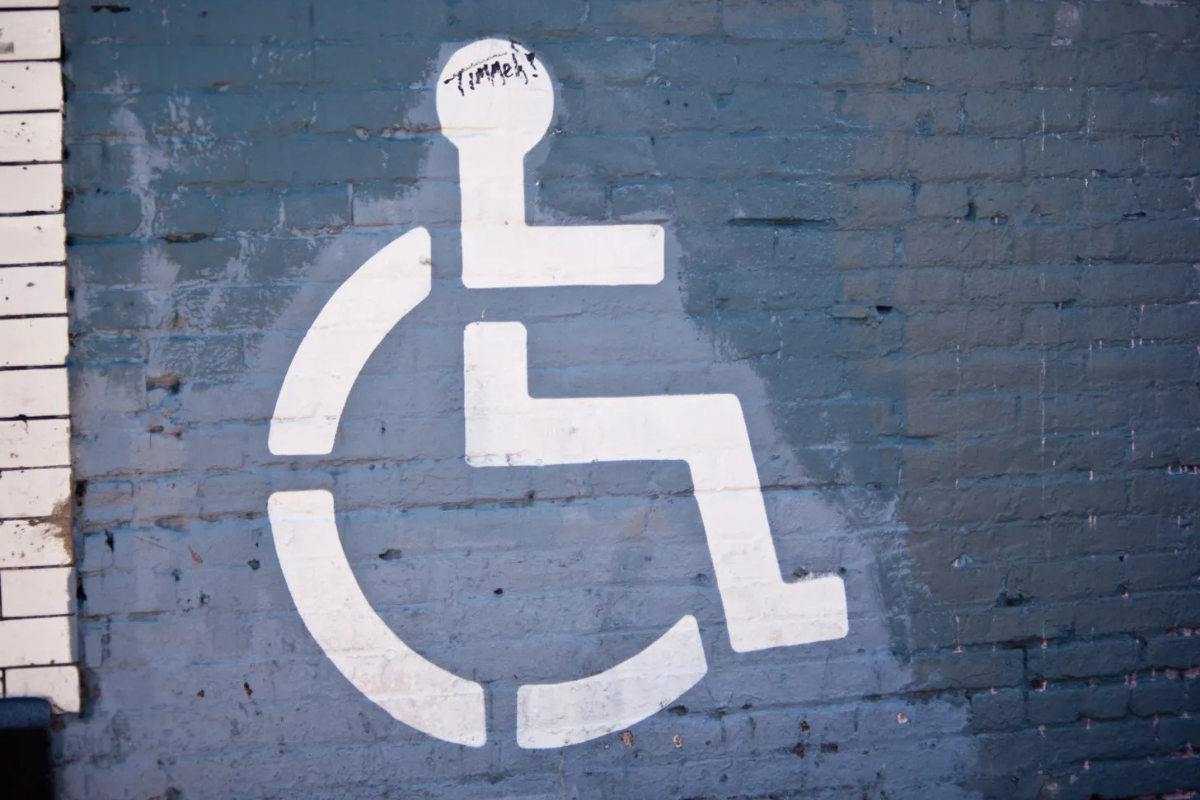 White wheelchair symbol stenciled on a blue brick wall