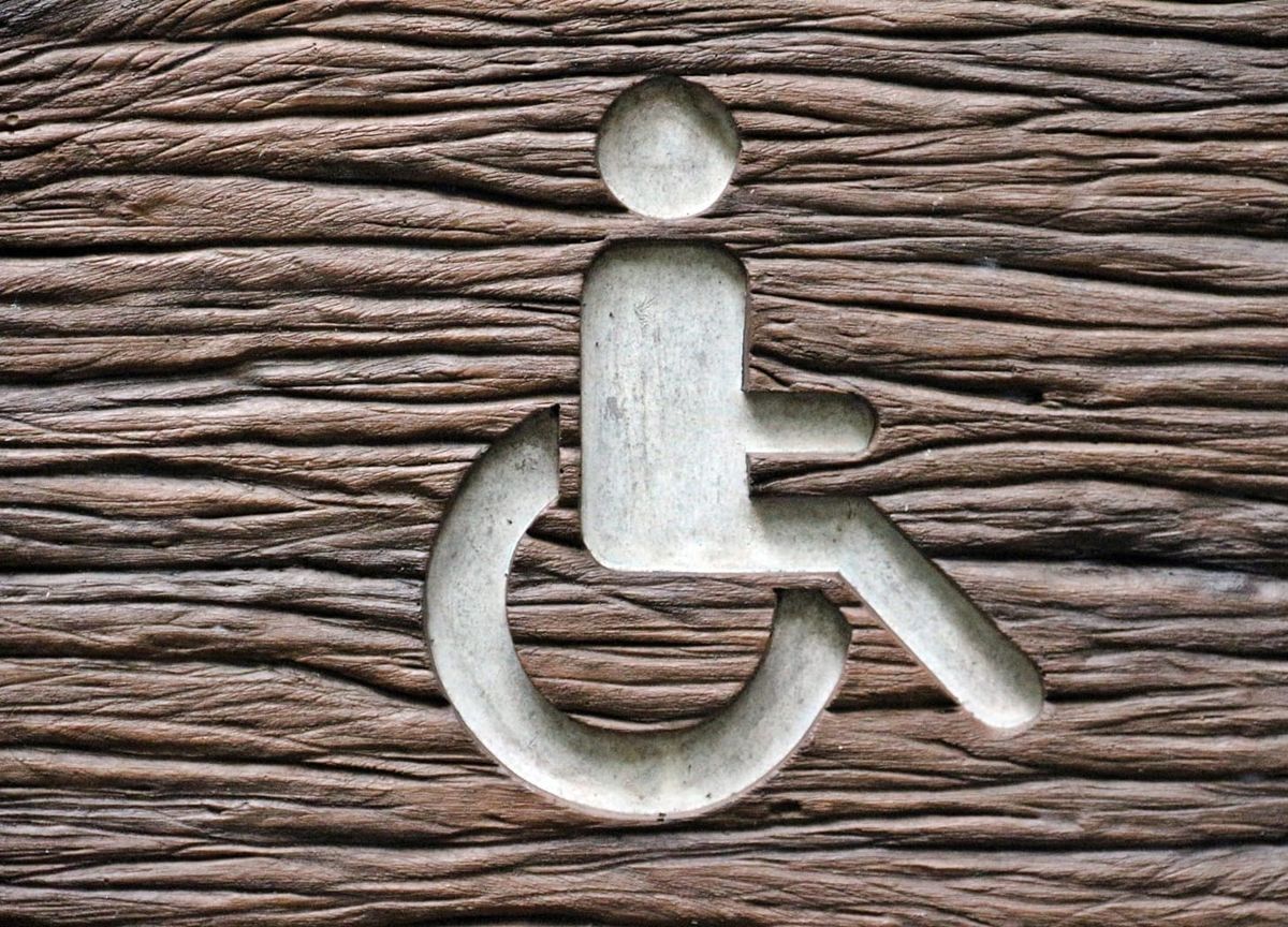 Wheelchair symbol carved into a deeply textured wood surface