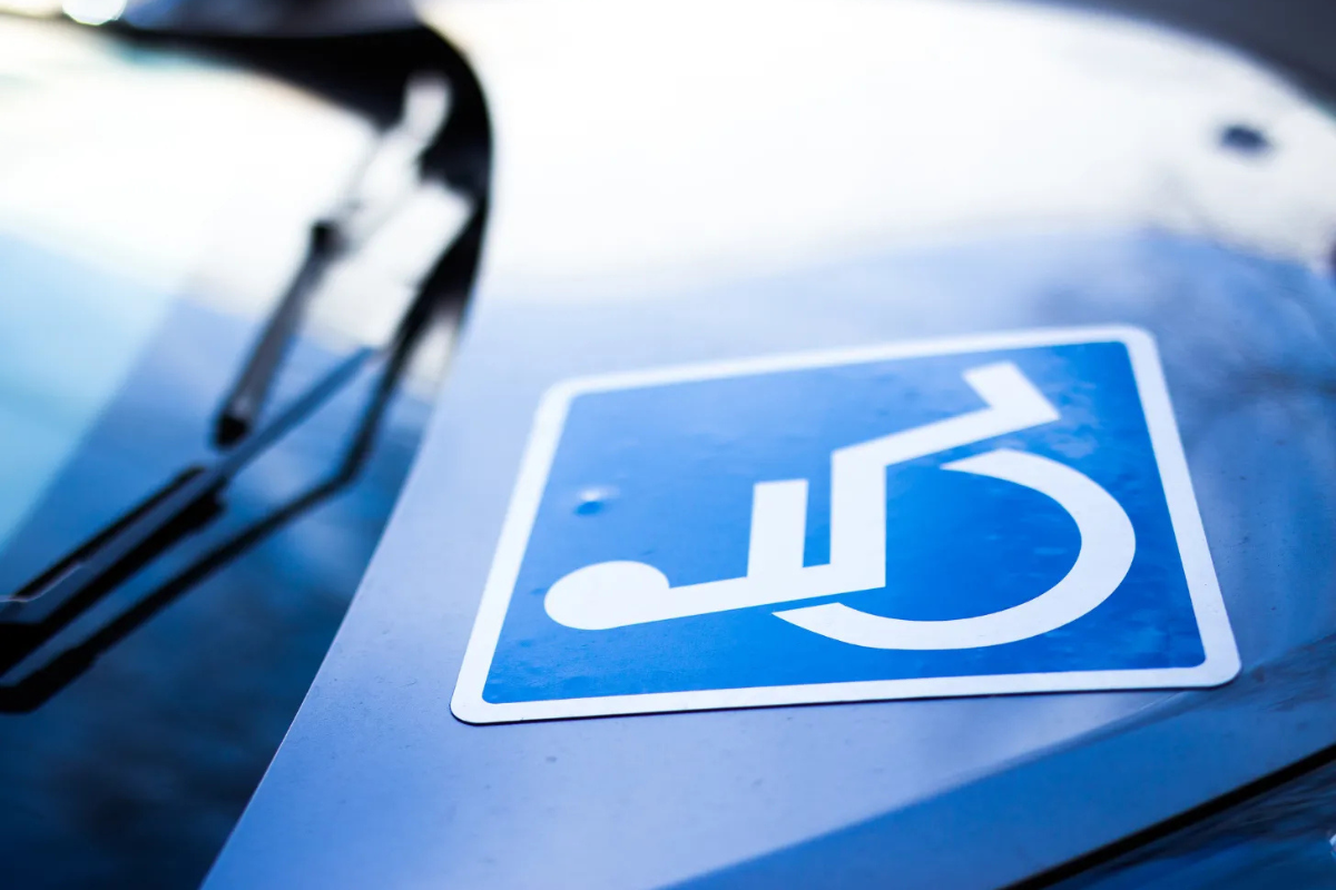 White on blue wheelchair sticker on the hood of a blue car