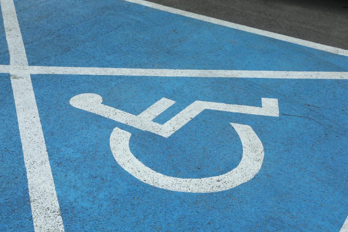 White on blue wheelchair symbol and lines marking accessible parking space on paveme