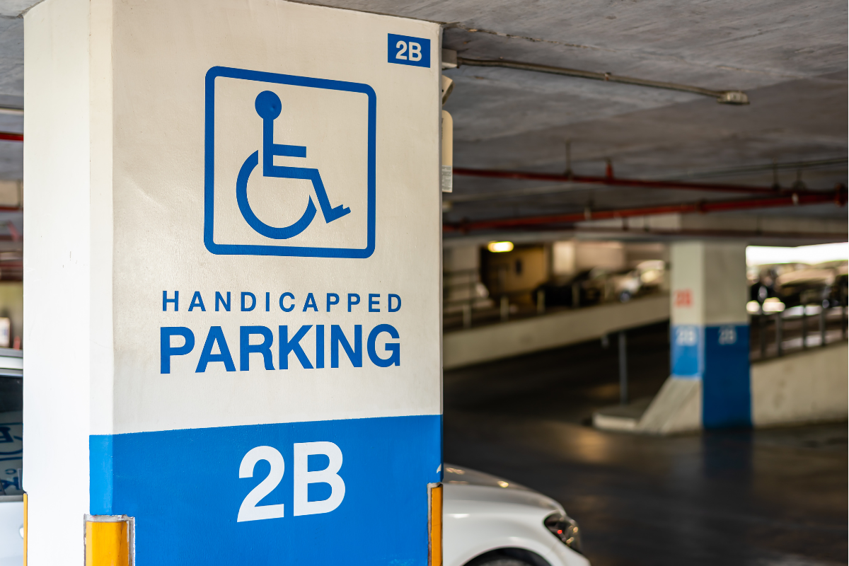 "Handicapped Parking" sign with a blue wheelchair symbol inside a public garag
