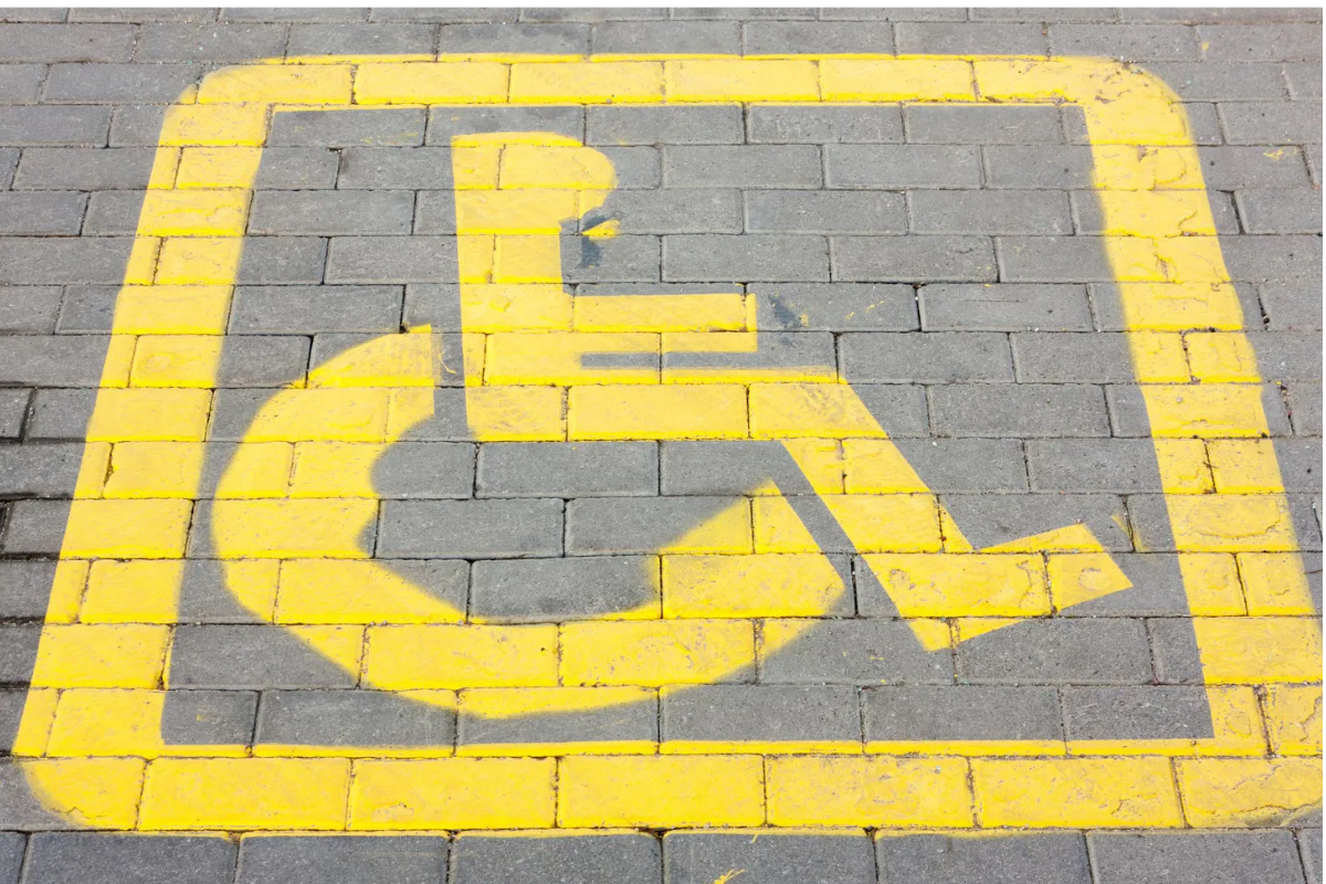 Yellow stenciled wheelchair symbol on gray brick