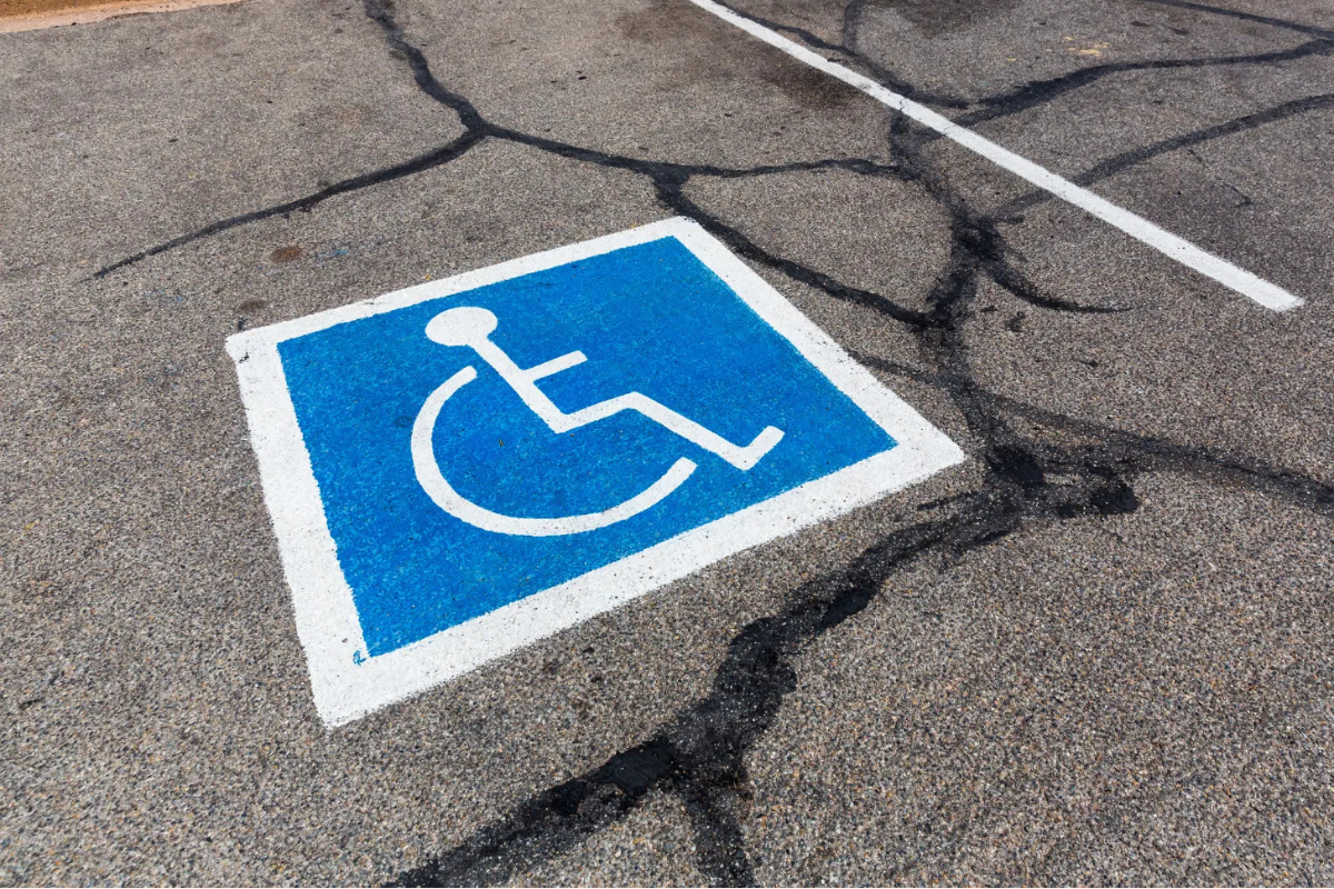 White on blue wheelchair symbol painted onto an accessible parking space with cracked pavement