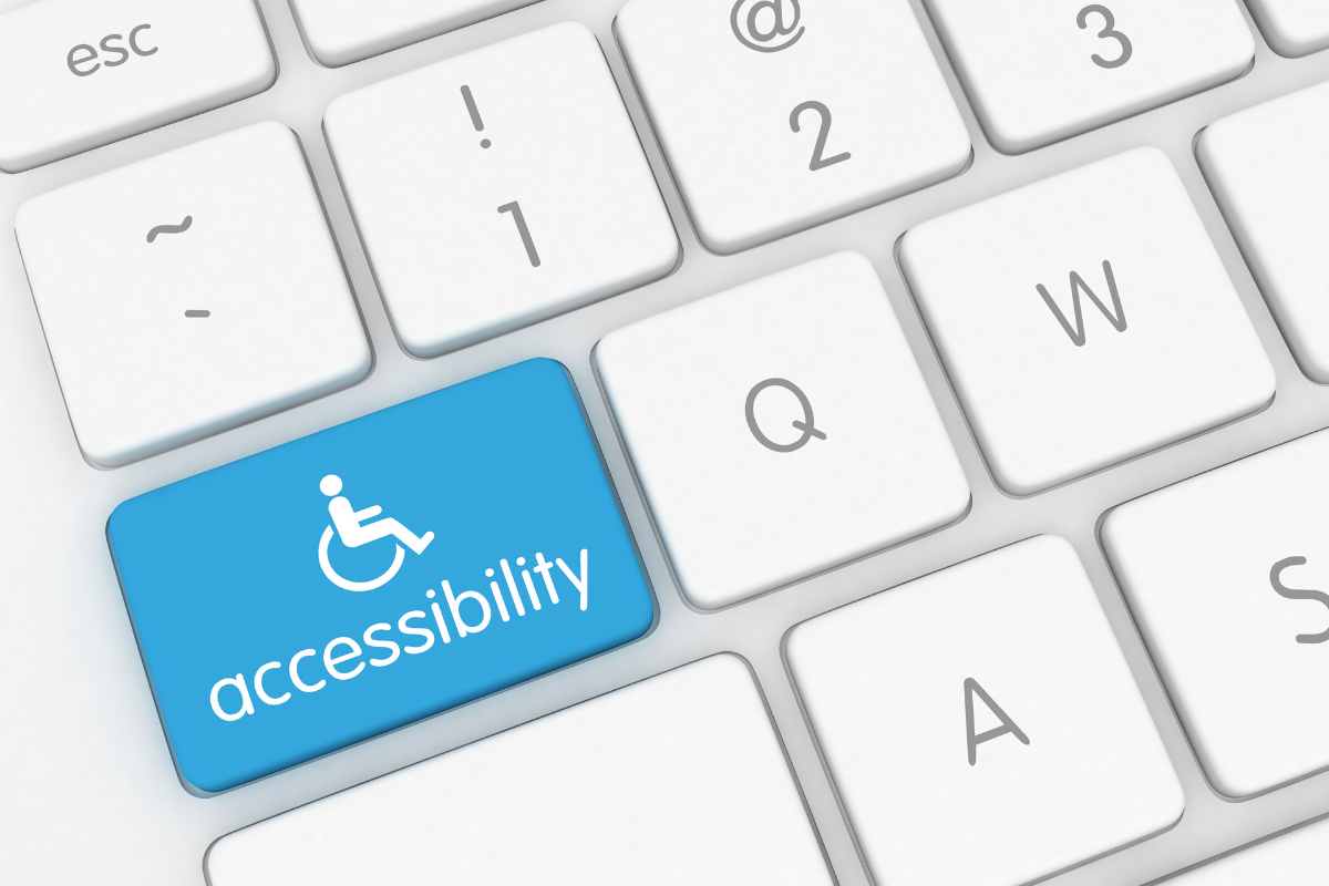 Closeup of a computer keyboard with one blue key labeled with a white wheelchair symbol and the word "accessibility" in white print