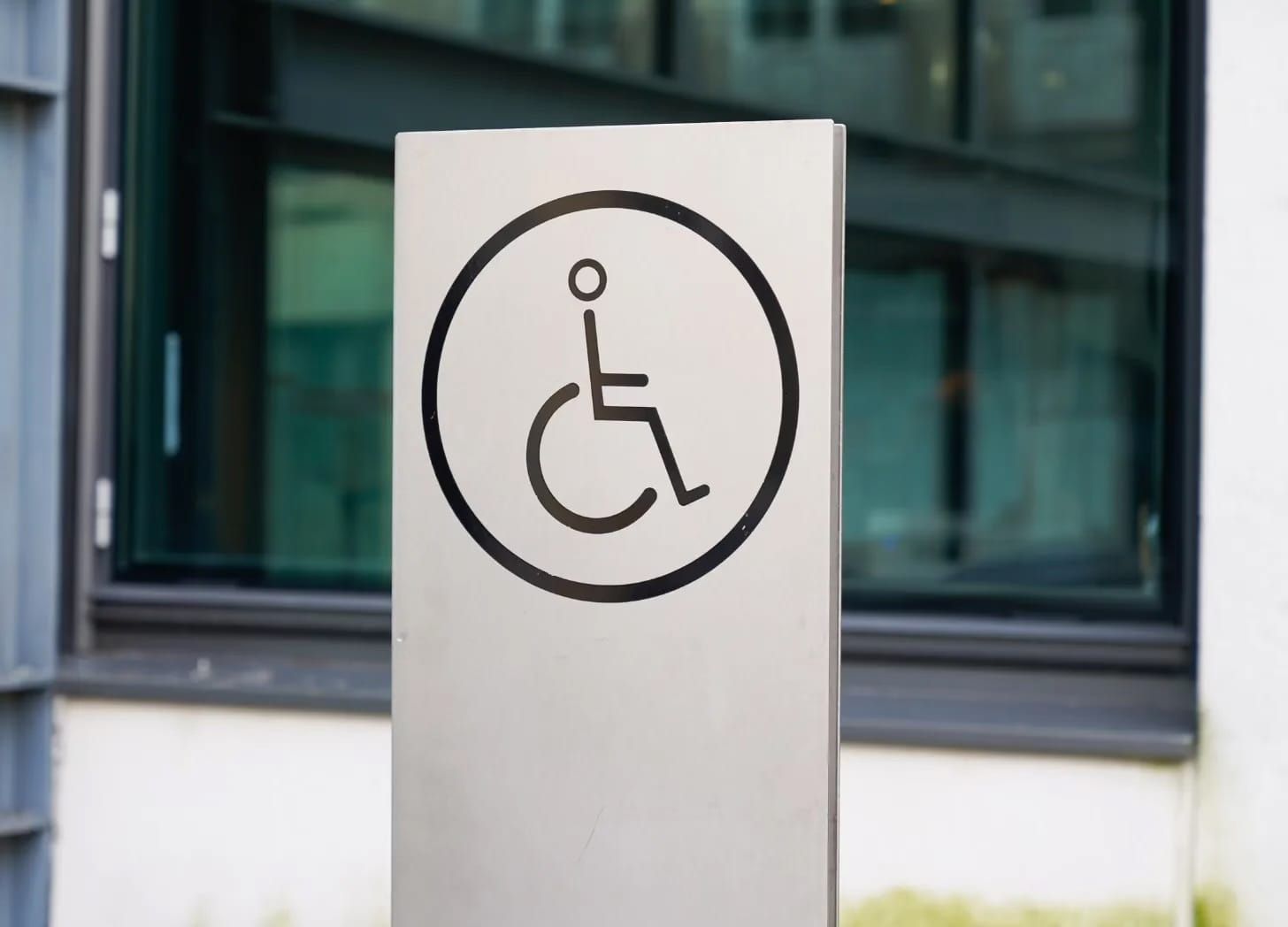 Black on metal grey wheelchair symbol in a black circle on an upright sign