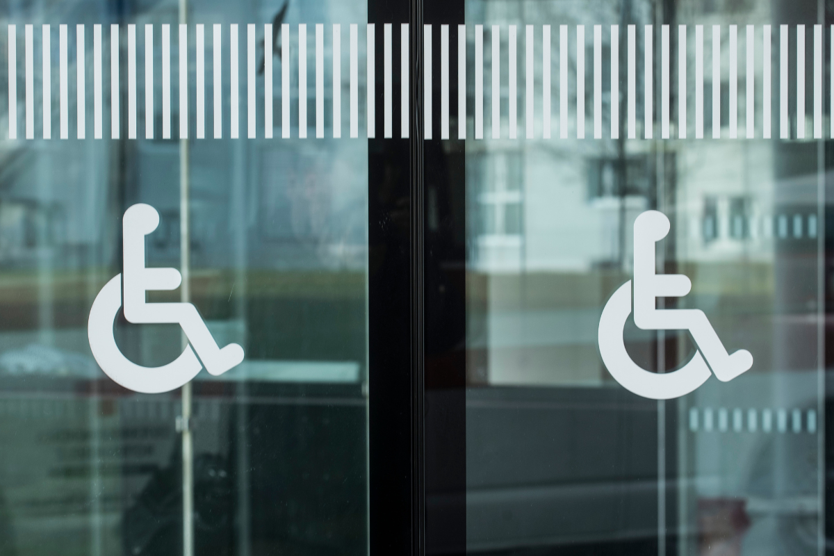 Two white wheelchair symbol decals on glass doors