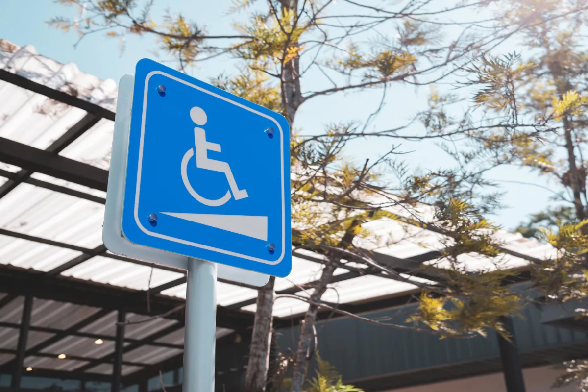 White on blue wheelchair symbol on a vertical sign marking an accessible outdoor ramp