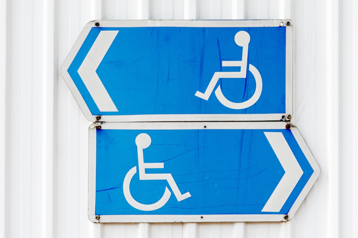 Two white on blue wheelchair sumbol directional signs one pointing left oright