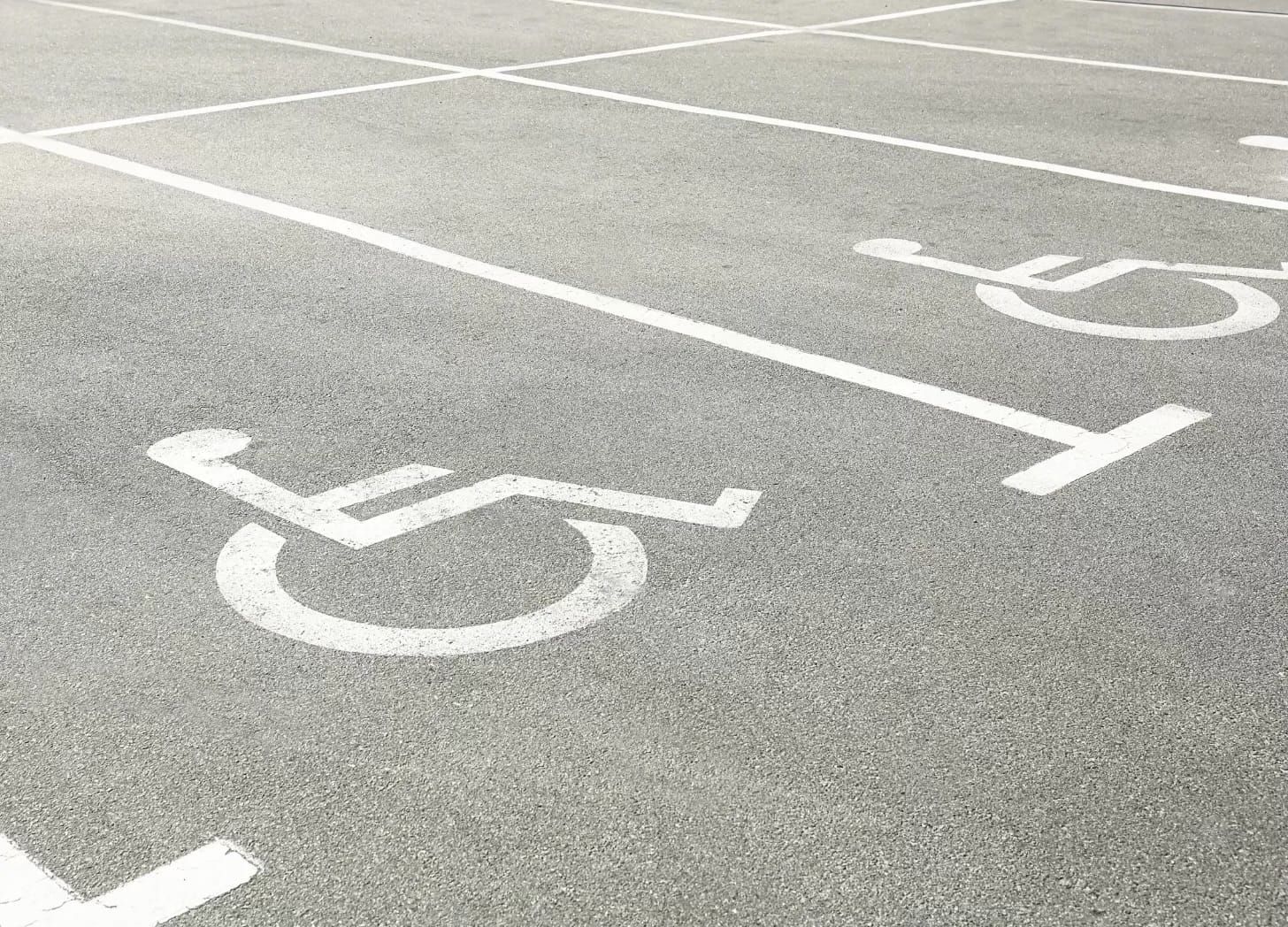 White wheelchair symbols and parking lines on light grey pavemen