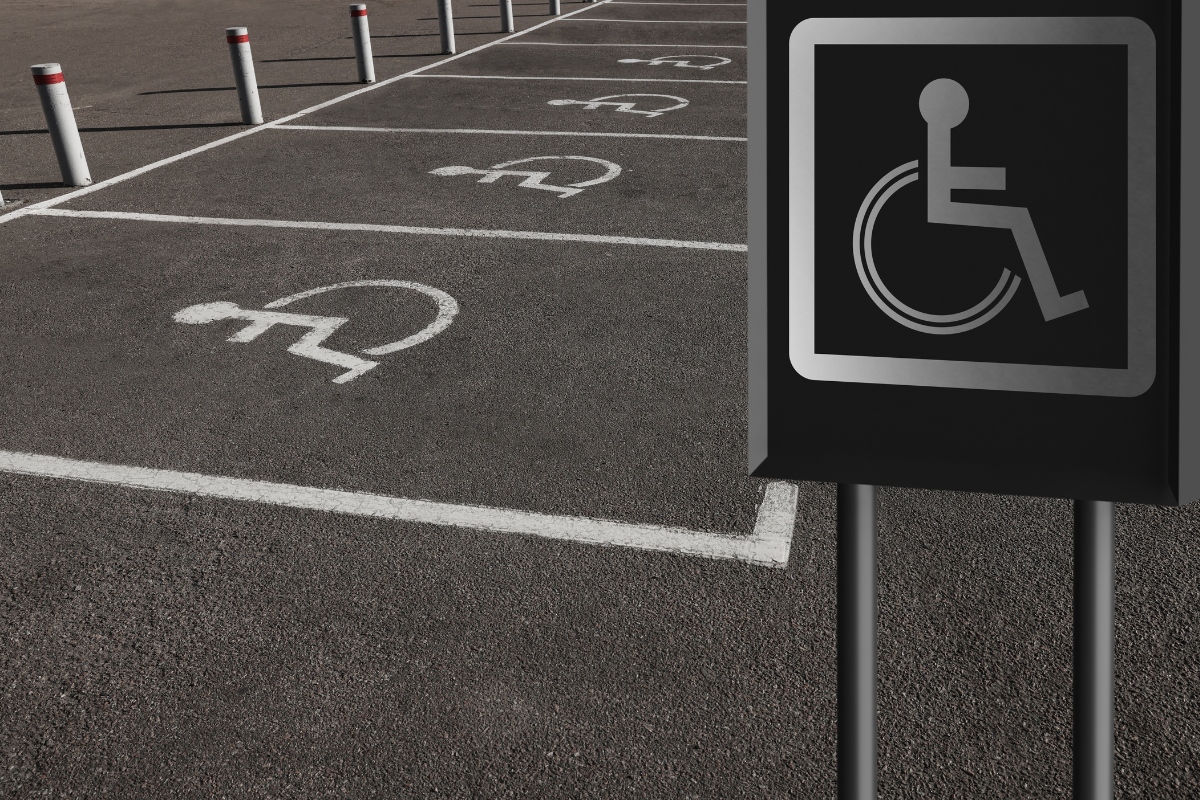 White on black upright wheelchair sign in front of row of accessible parking spaces