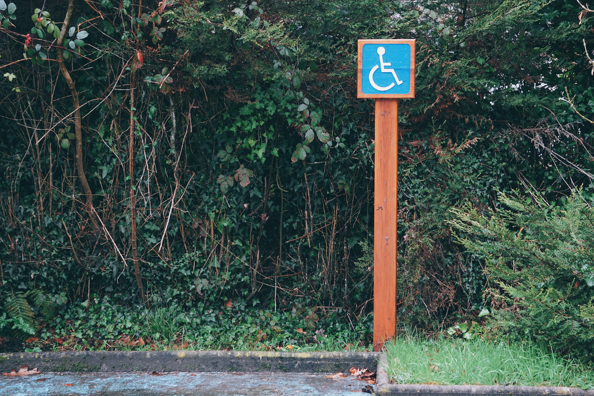 Small white on blue square wheelchair symbol sign on a tall cedar post