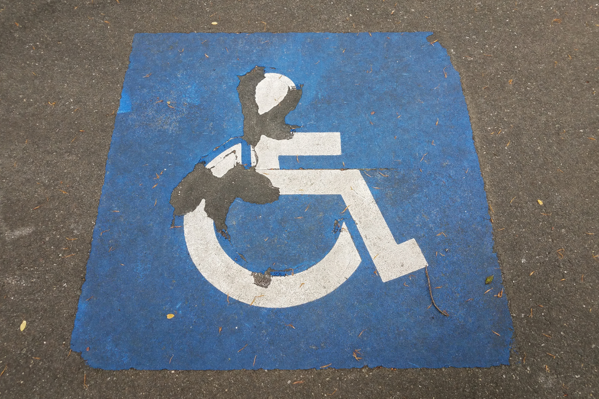 Peeling, eroded white wheelchair on blue painted on paveme
