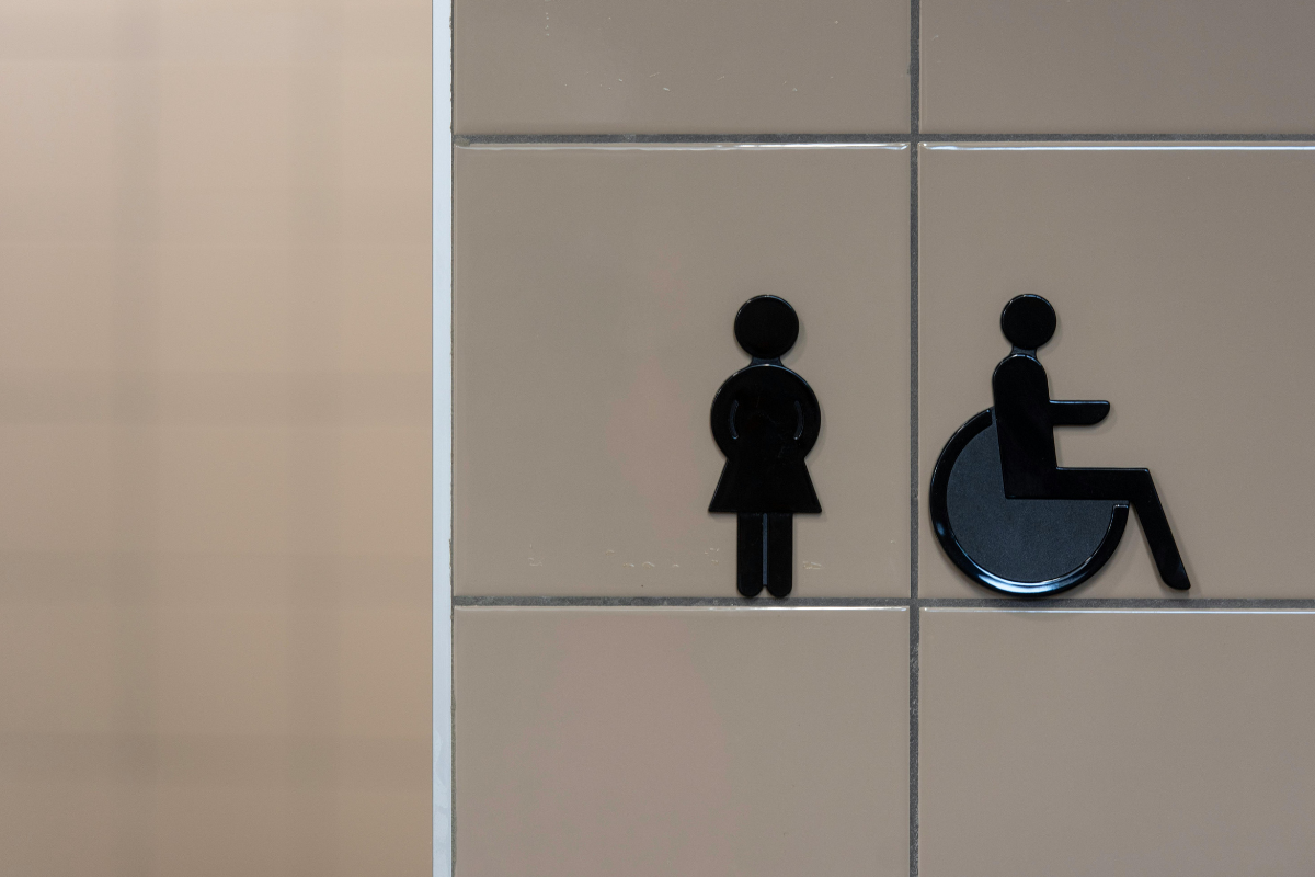 A nondisabled symbol and wheelchair user symbol mounted on a tile wall