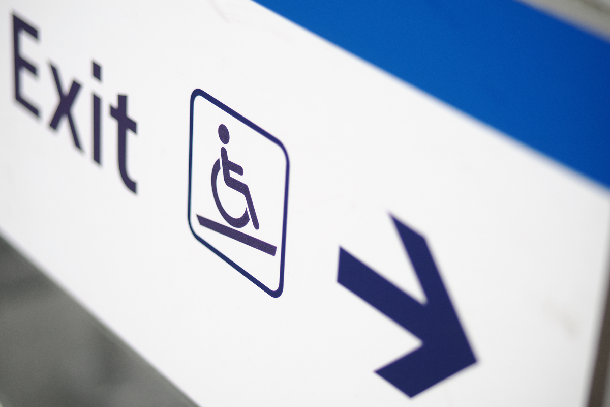 Blue on white wheelchair symbol sign marking the way to an exit