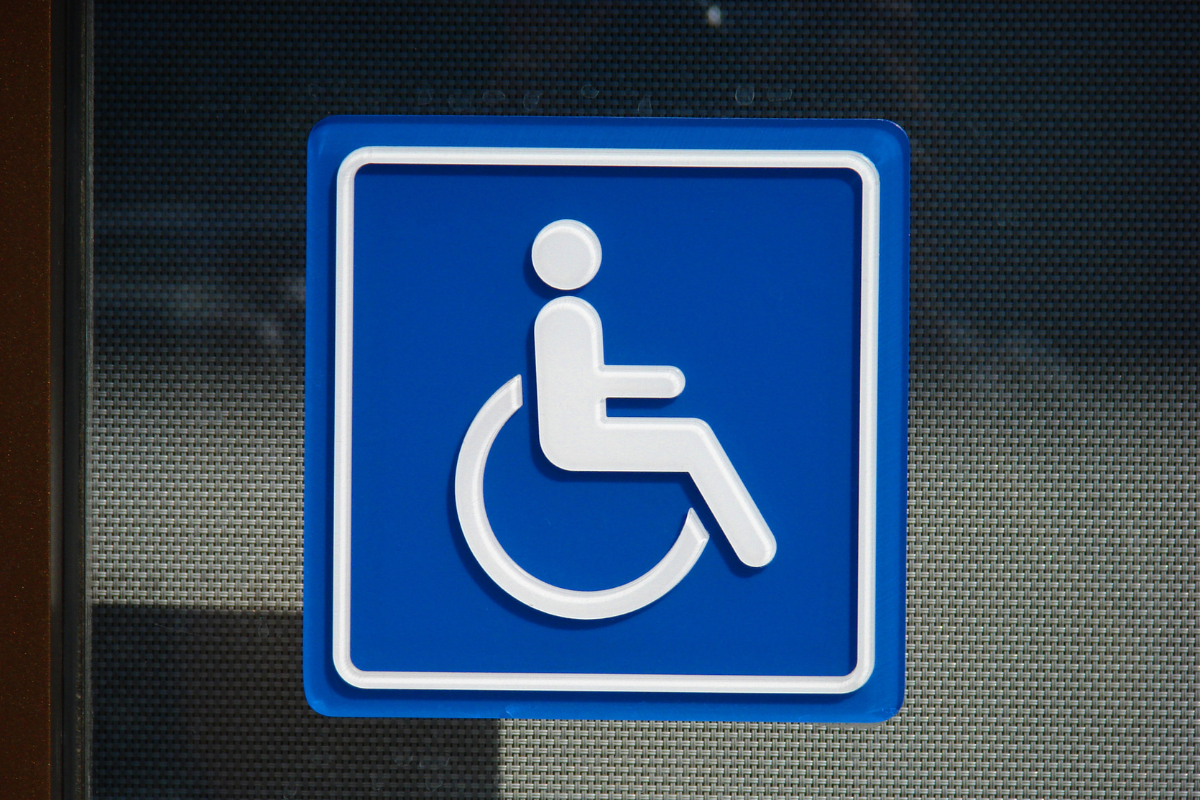 White on blue wheelchair sign mounted on a glass doo