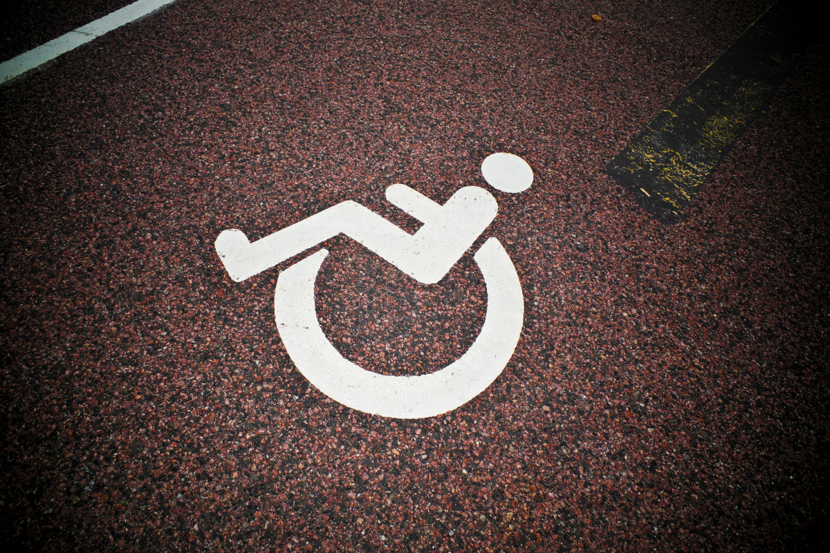 White wheelchair symbol painted onto brown gravely pavement