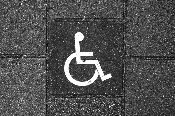 White wheelchair symbol on a black brick wal