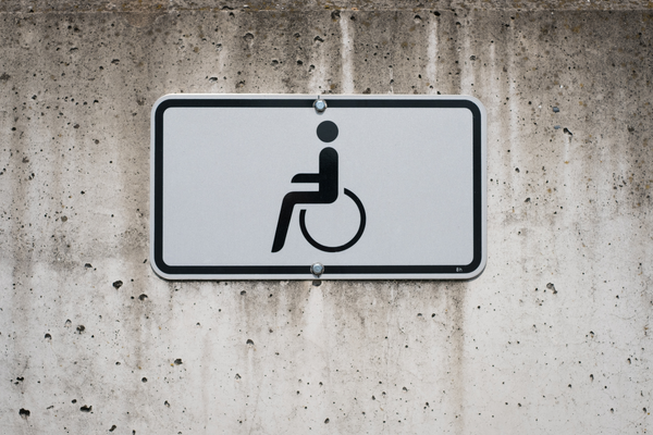 Black on white wheelchair symbol sign mounted on a streaked cement wall