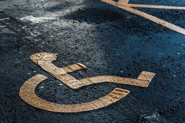 White on blue wheelchair symbol on rough pavement