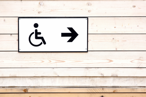 Black on white wheelchair symbol sign with right-pointing right arrow