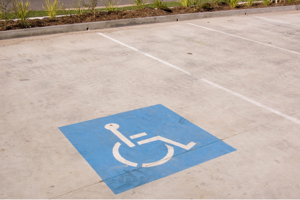 White on blue wheelchair symbol painted on light pavement of accessible parking space