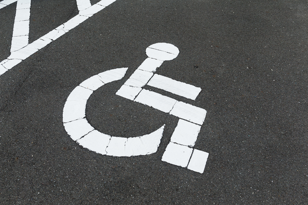 White wheelchair symbol stenciled on black pavement