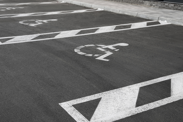 White wheelchair symbols and lines marking row of accessible parking spaces on black pavement