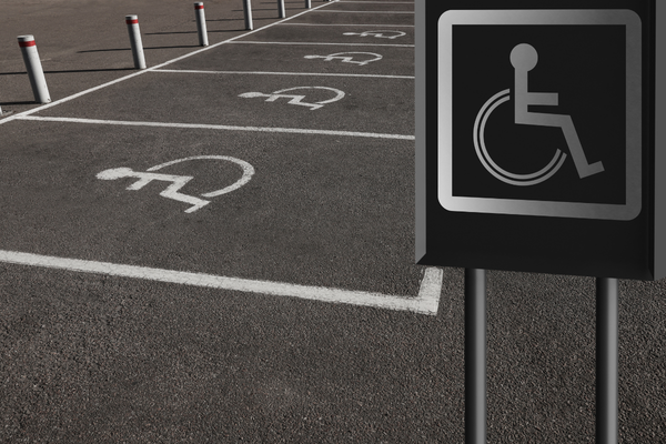 White on black upright wheelchair sign in front of row of accessible parking spaces