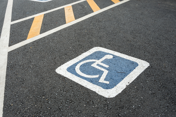 White on blue wheelchair symbol painted on pavement marking accessible parking space