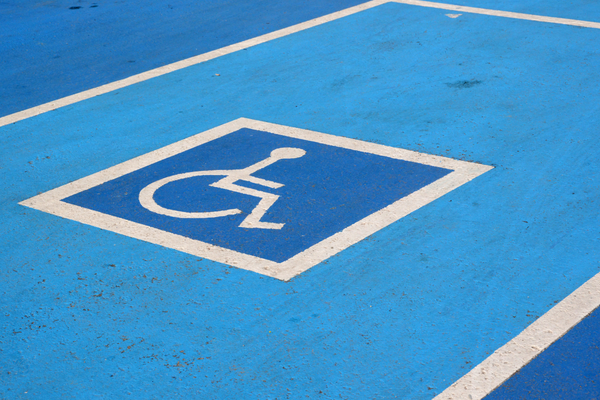 White on blue wheelchair symbol marking blue painted accessible parking space