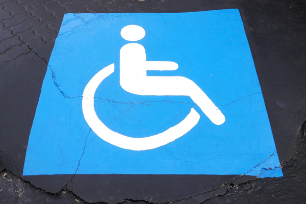 White on blue wheelchair symbol painted onto black pavemen