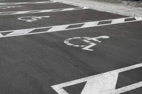 White wheelchair symbols stenciled on pavement, marking a row of accessible parking spaces
