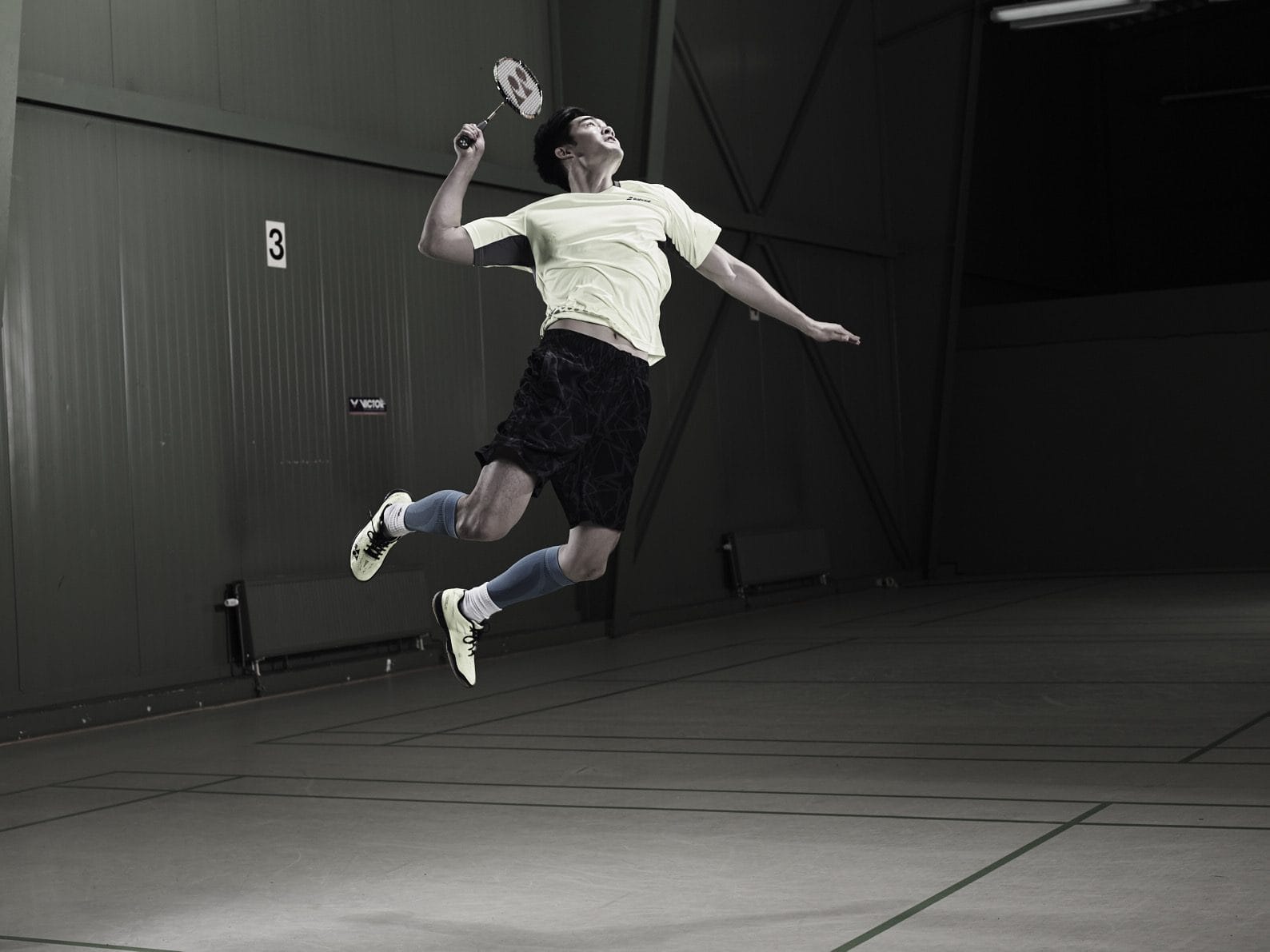 Martin Zhang mid-air during a competitive badminton jump smash