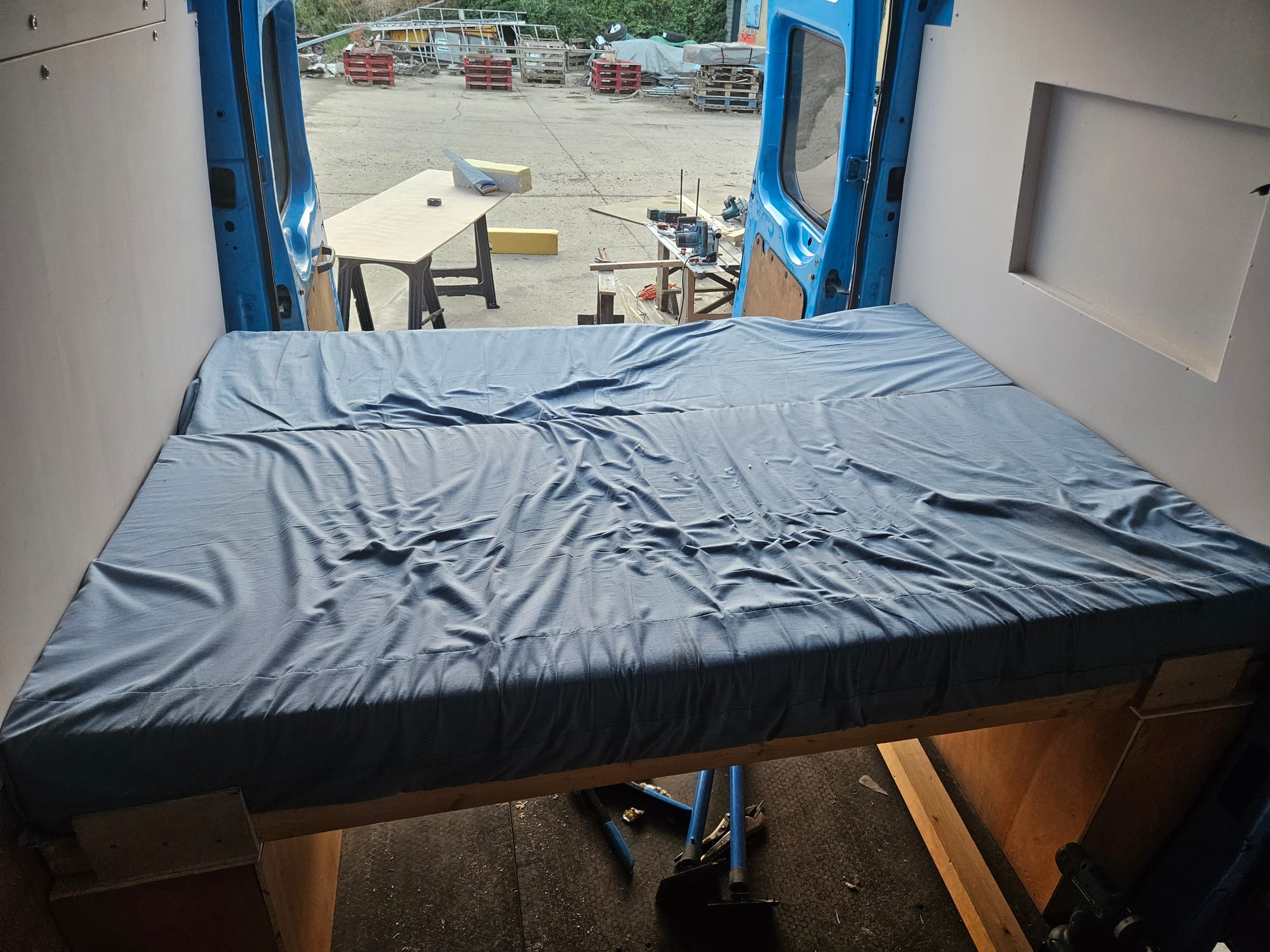 A bed fixed across the back of a living van