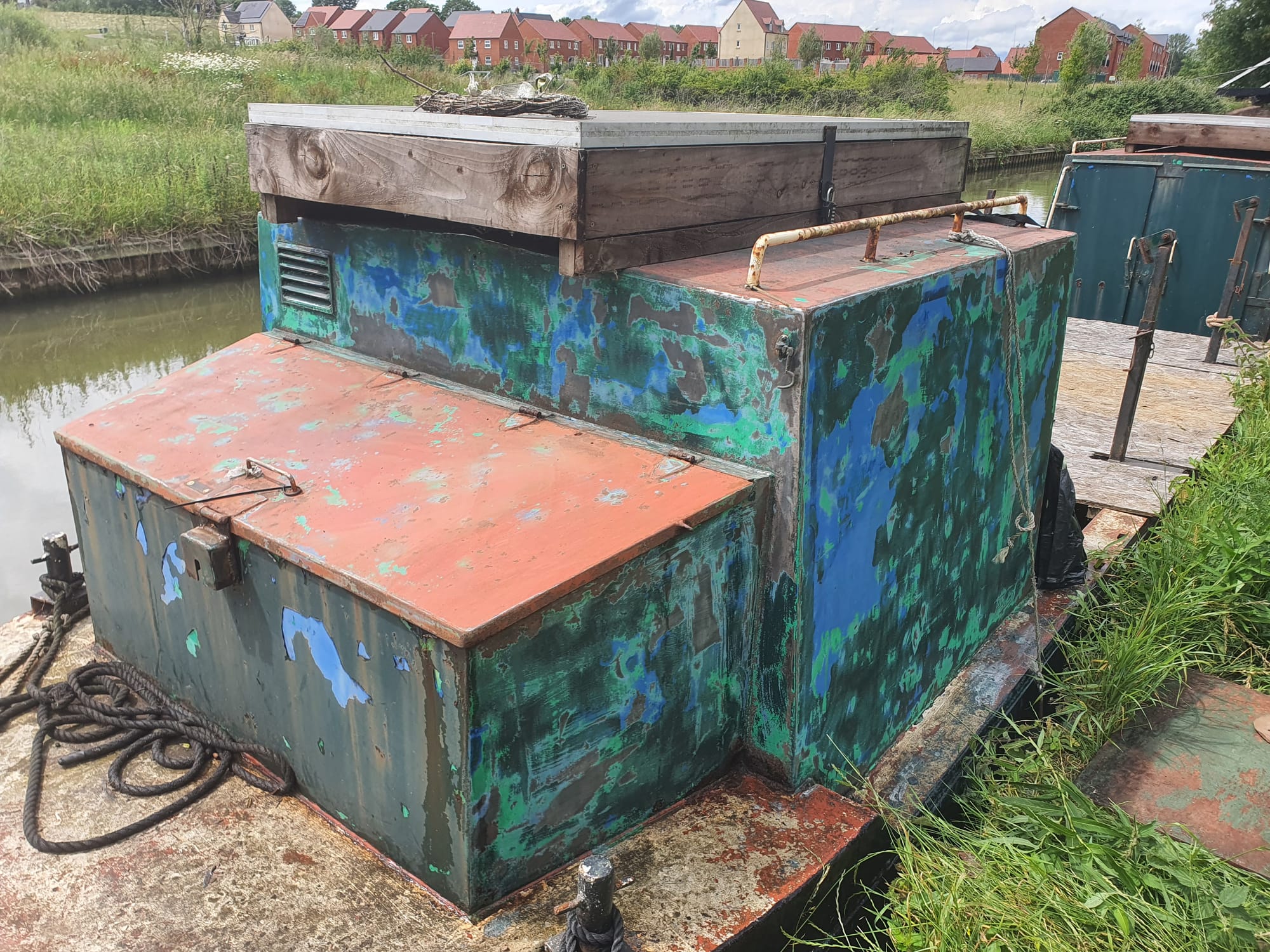A metal box cabin with paint sanded and showing a mix of blue and green in the old paint