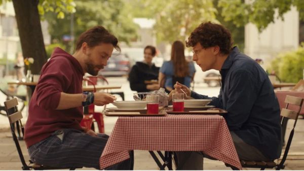 Kieran Culkin and Jesse Eisenberg in an outdoor cafe in a still from the film A Real Pain