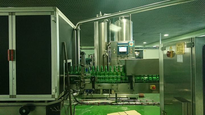 Green bottles on a conveyor belt in a factory.
