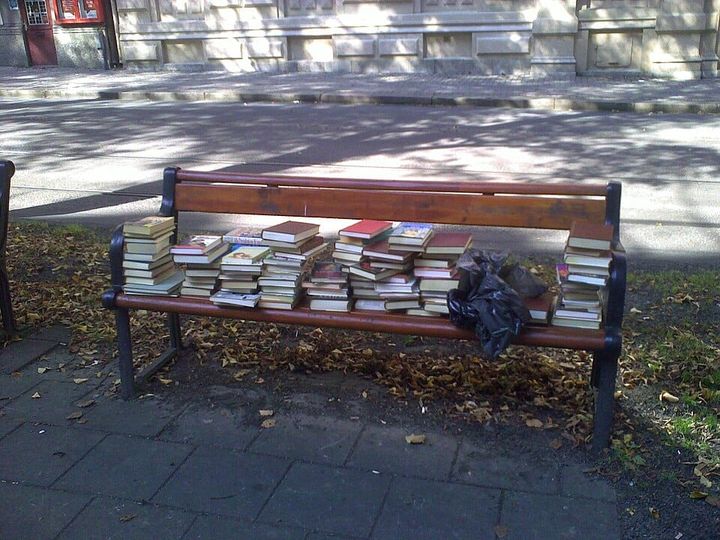 a park bench covered in piles of books