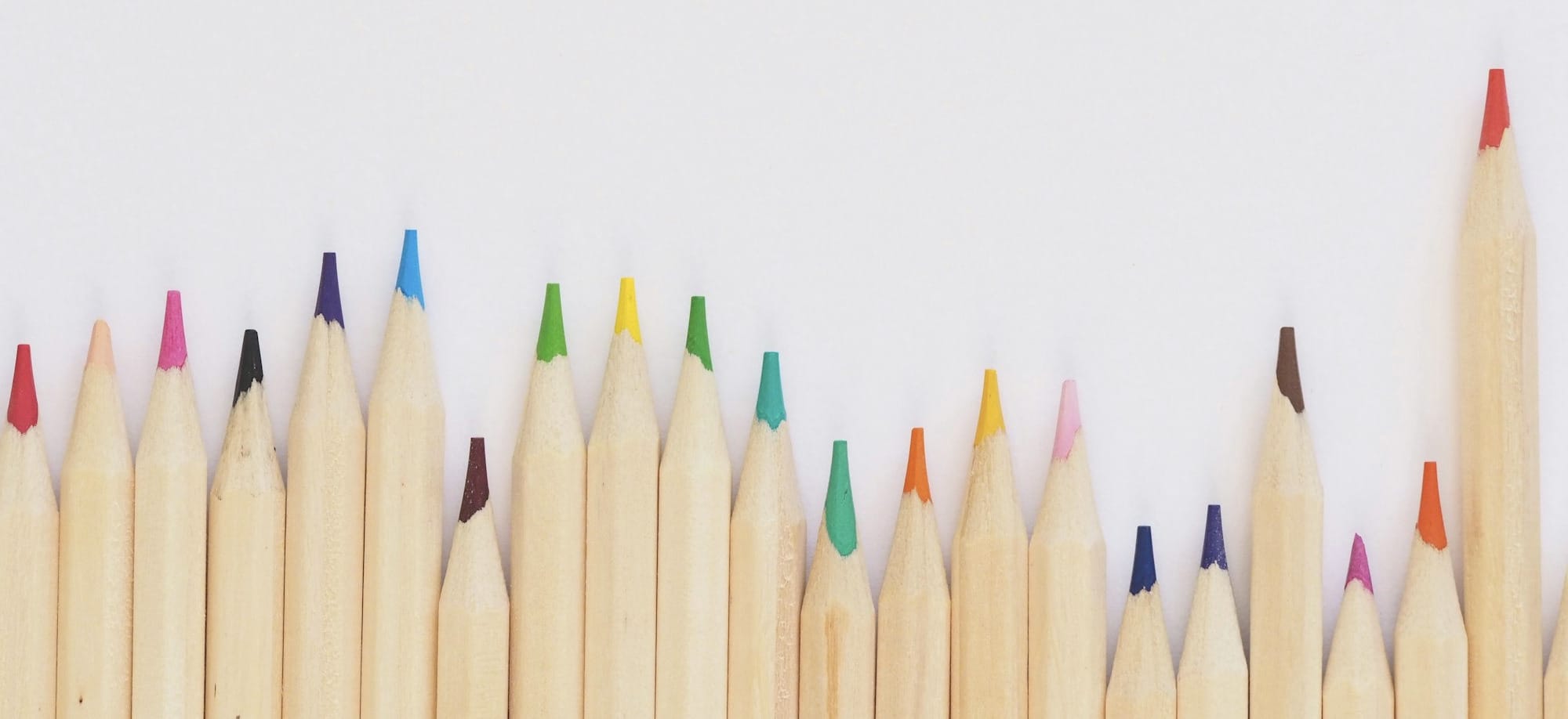 colored pencil lined up on top of white surface