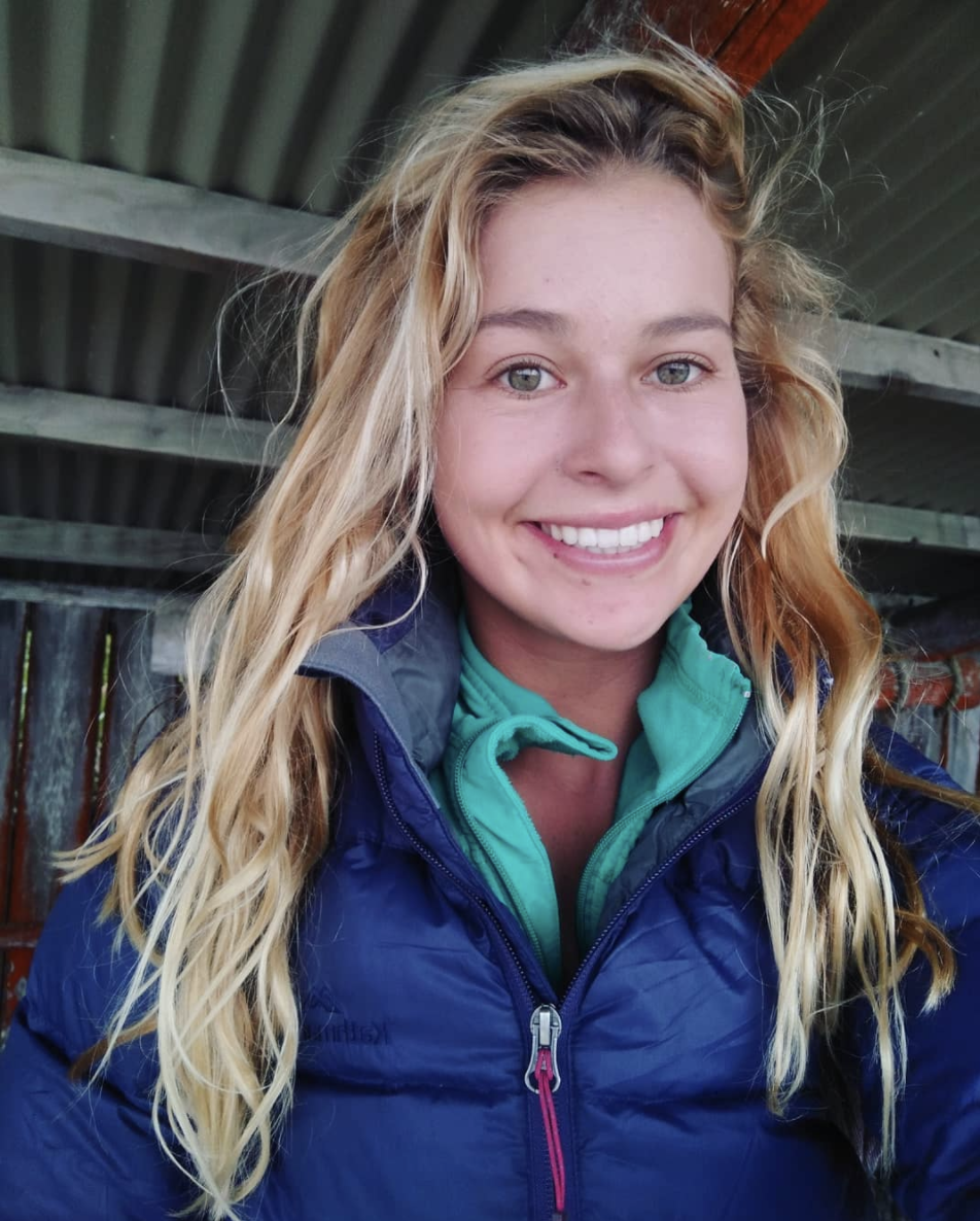 Daisy Kermode, Coastal Cleanup Crew founder, smiling at the camper in a navy blue puffer jacket.