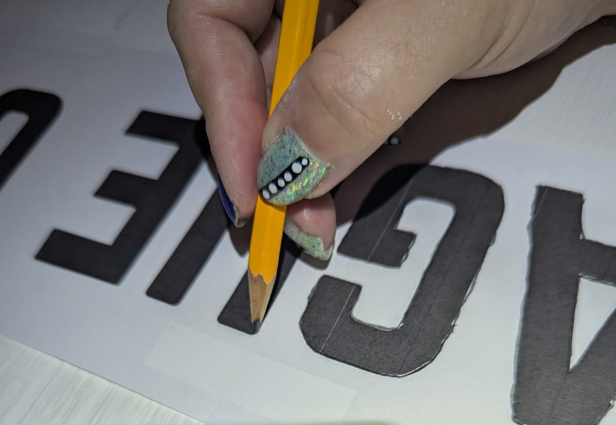 A close-up shot of the letter from the front, with Wiley's hand using a pencil to trace the outlines of the letters.