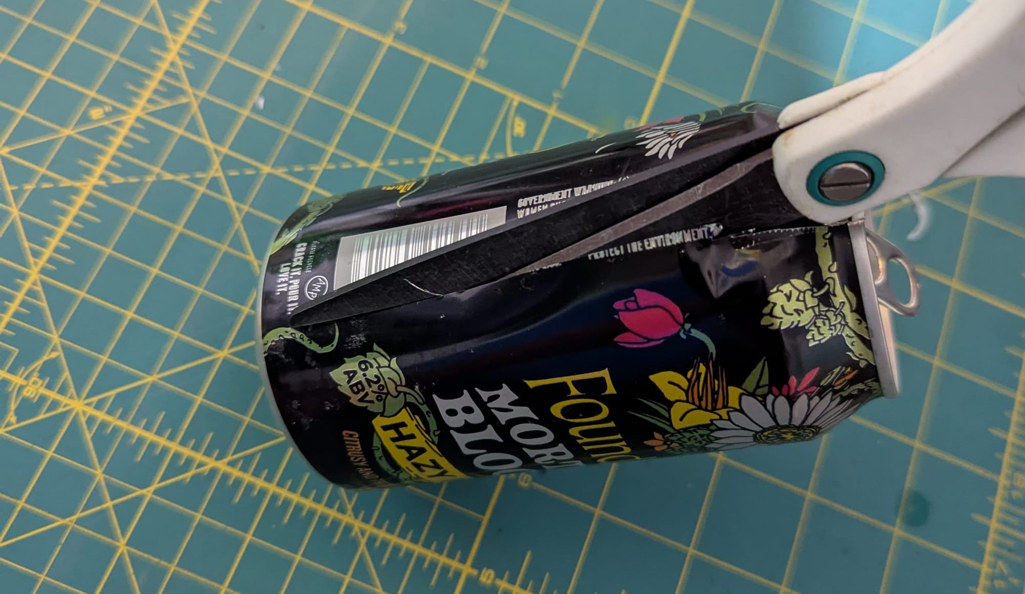 a soda can being cut open with a pair of scissors