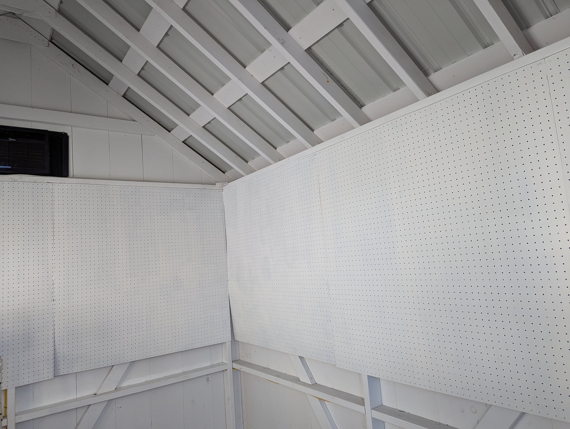The corner of the Artisan Market cabin, showing several pegboard panels that have been imperfectly painted white. They need at least two or three more coats of paint to achieve even coverage.