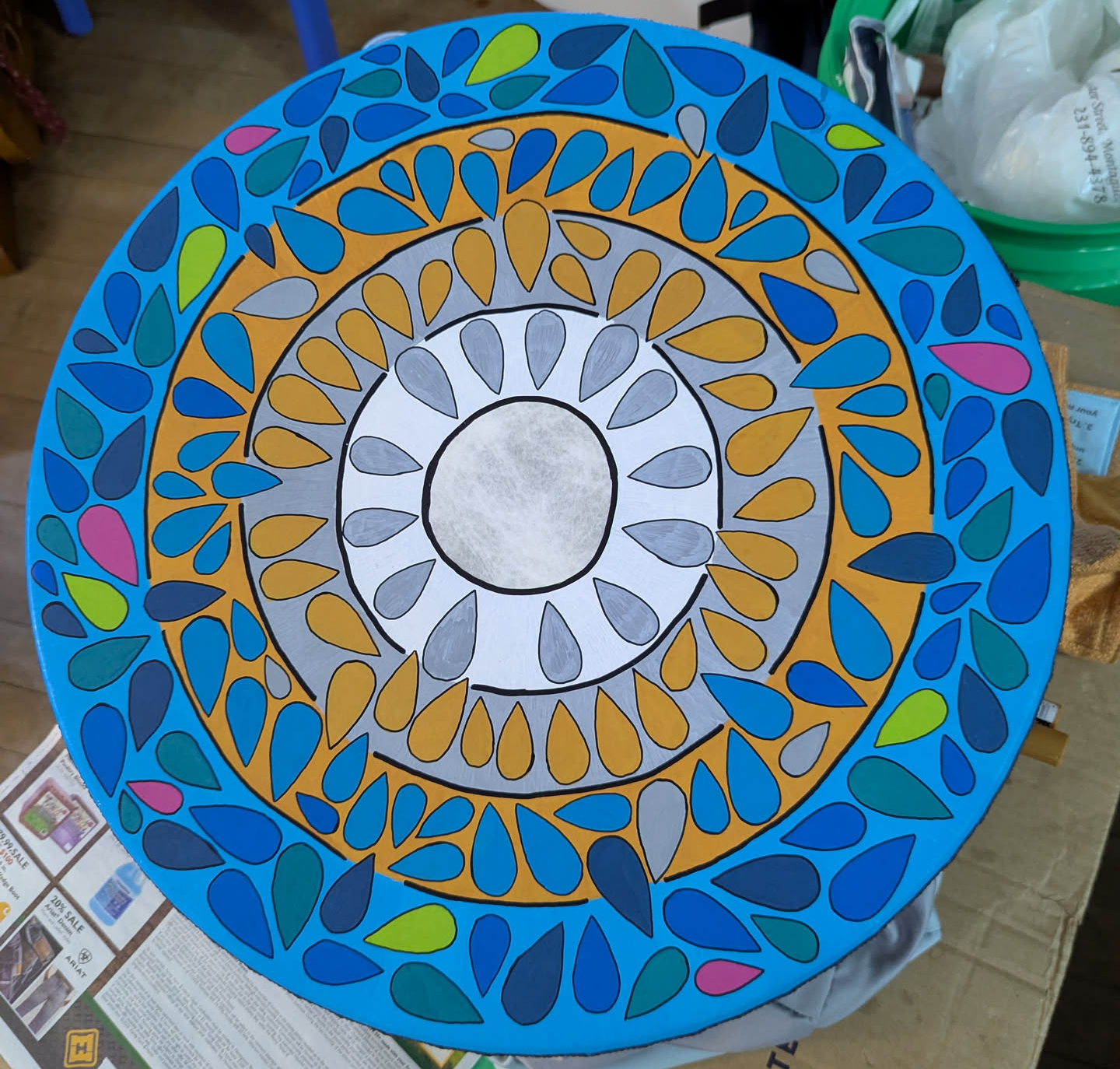 A brightly painted drum featuring concentric rings of color populated by teardrop shapes