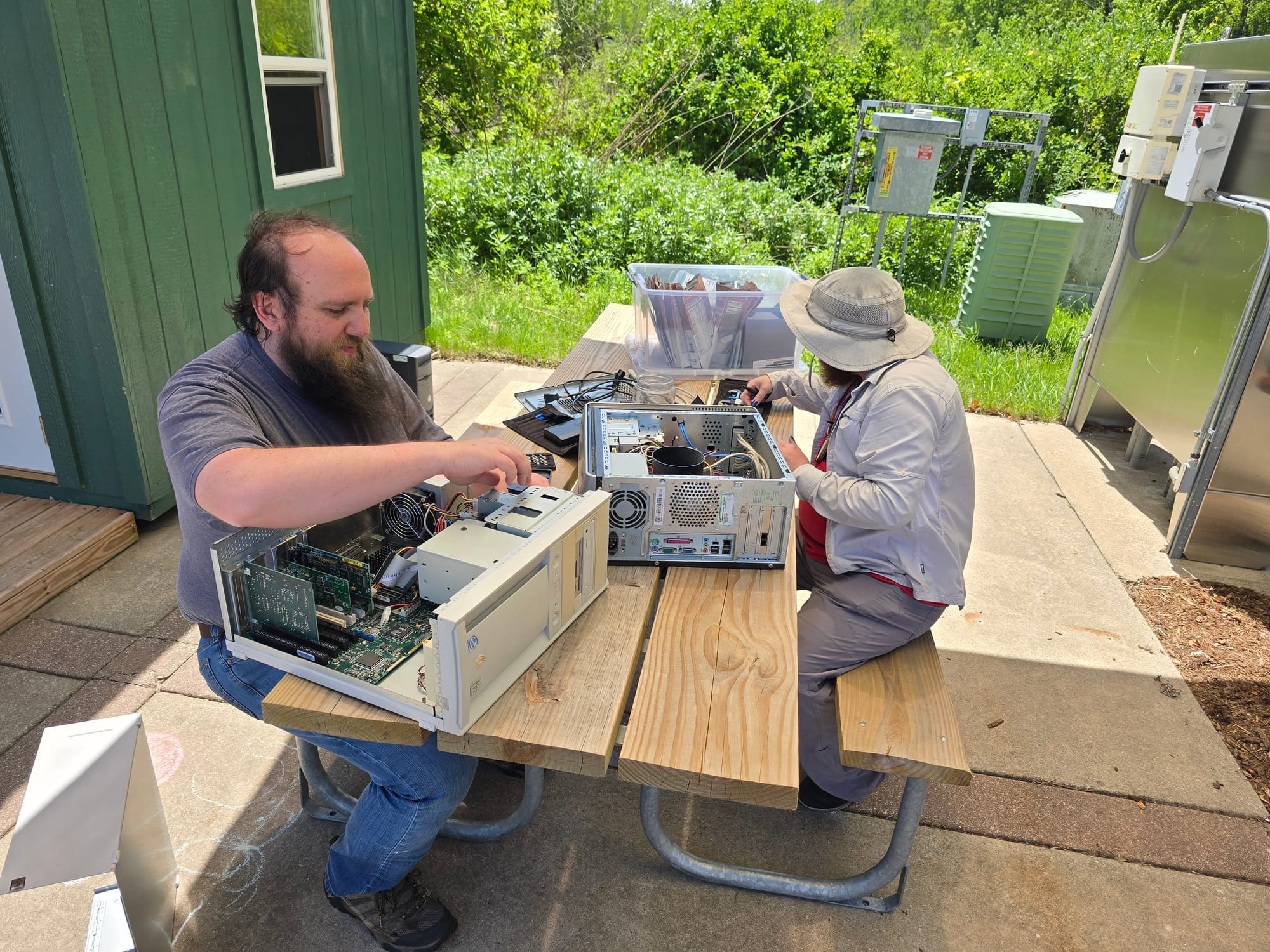 Nate and Wiley sitting at the Farmers' Market picnic table and disassembling a couple of old computers