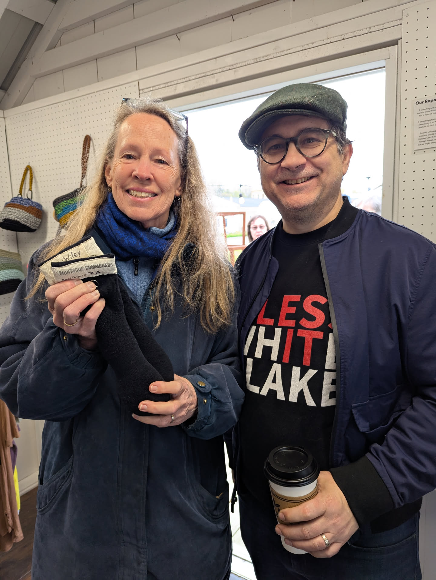 Susan and Leighton standing next to each other in the doorway to our shop. Susan is holding up the pair of boot dryers that she just bought.
