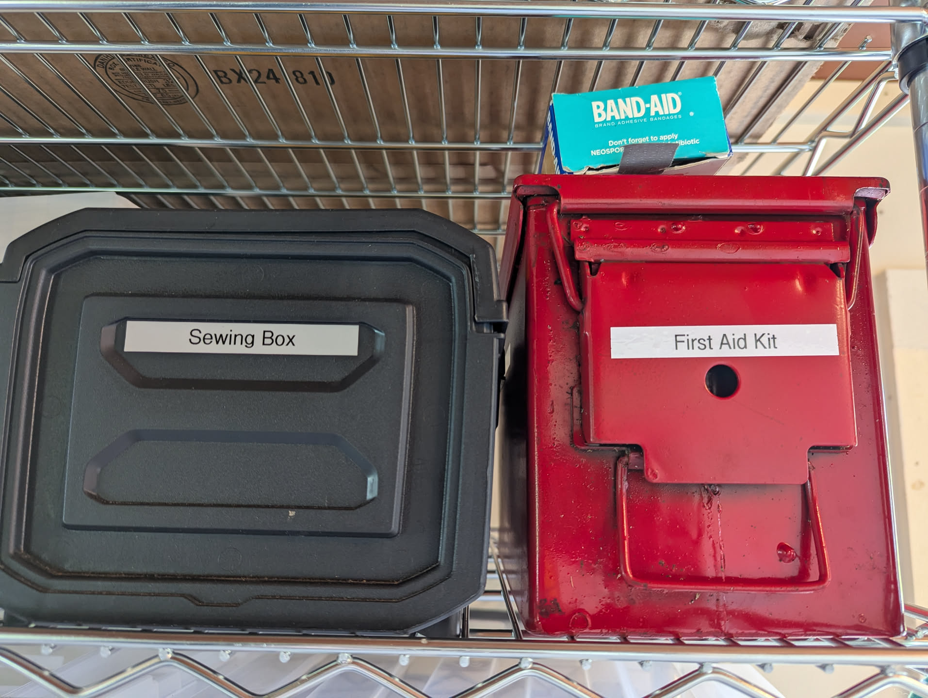 The sewing box and the first aid kit sitting next to each other on the top shelf by the door