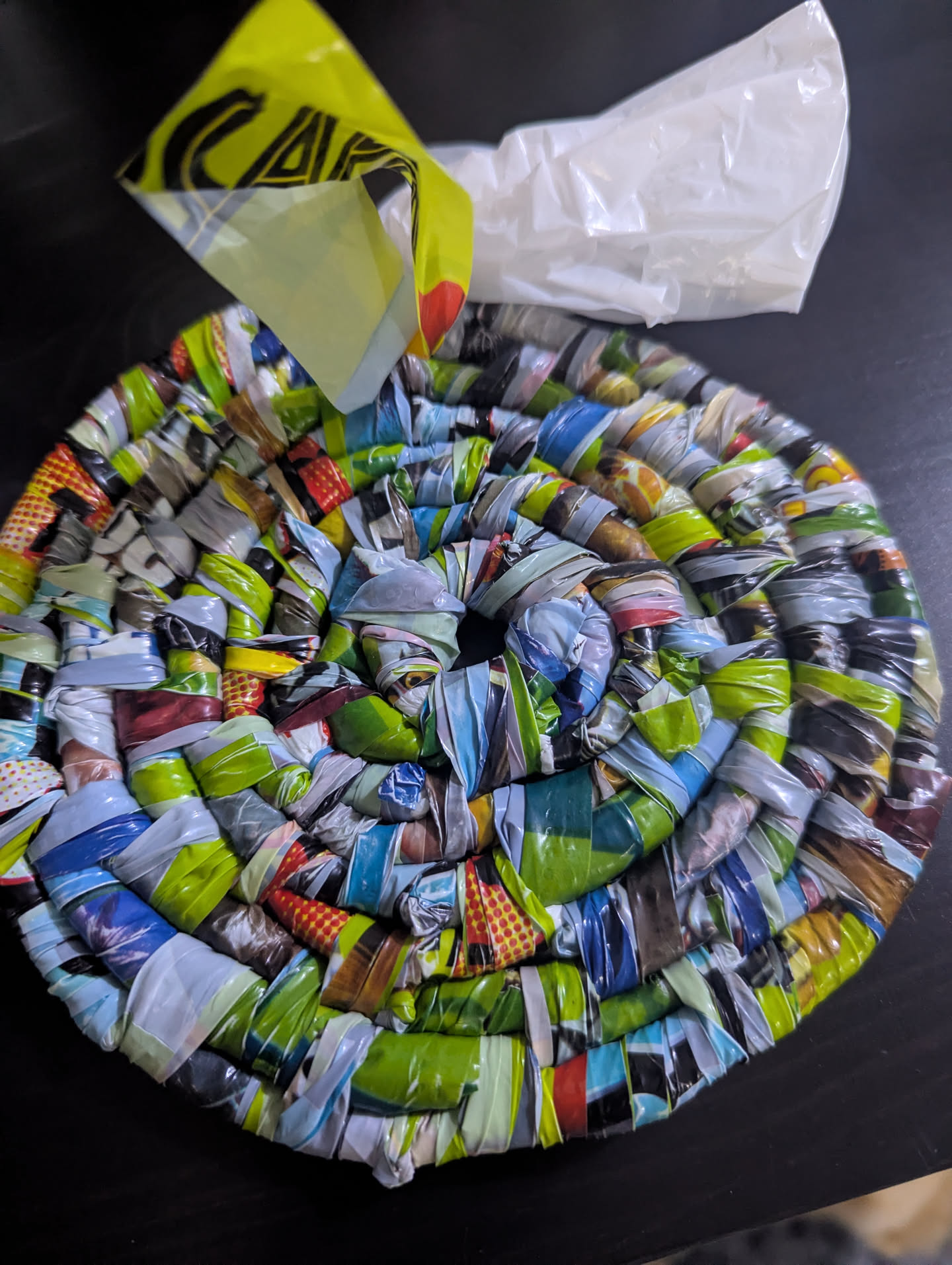 A circle of coiled basketry made out of brightly colored plastic bags