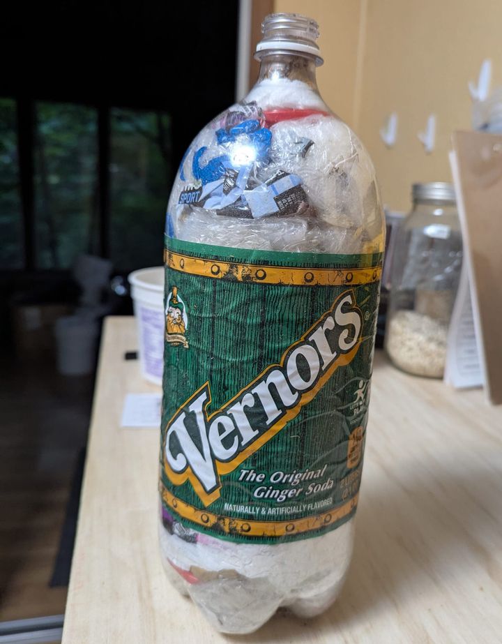 A 2-liter Vernor's bottle that has been filled with plastic shopping bags and other film plastic.