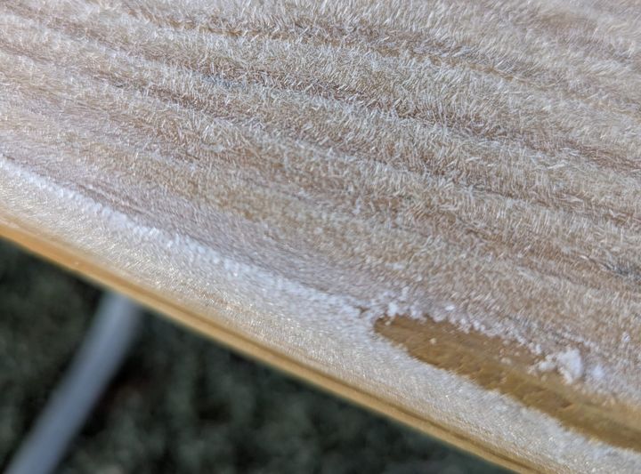 A closeup of a picnic table covered in tiny hairs made of frost